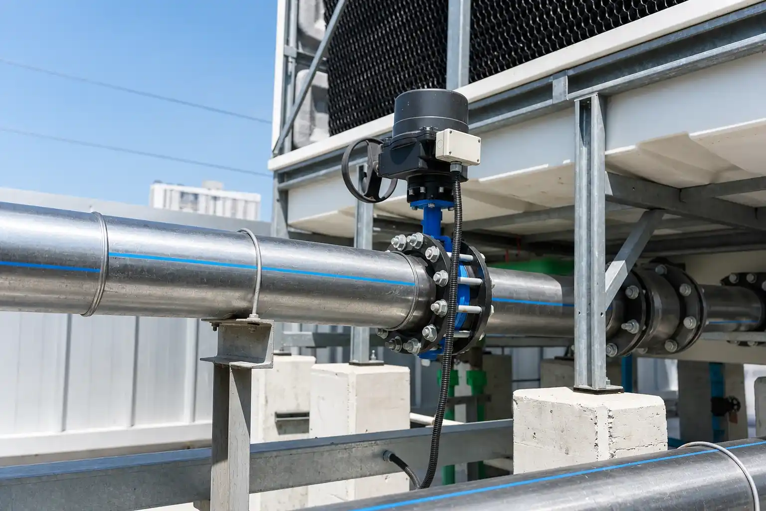 Large-bore butterfly valve with electric actuator installed on a water cooling pipeline at an industrial facility.